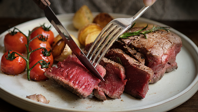 Grilled tomatoes on the vine, potatoes, and a sliced rare steak Grilled tomatoes on the vine, potatoes, and a sliced rare steak