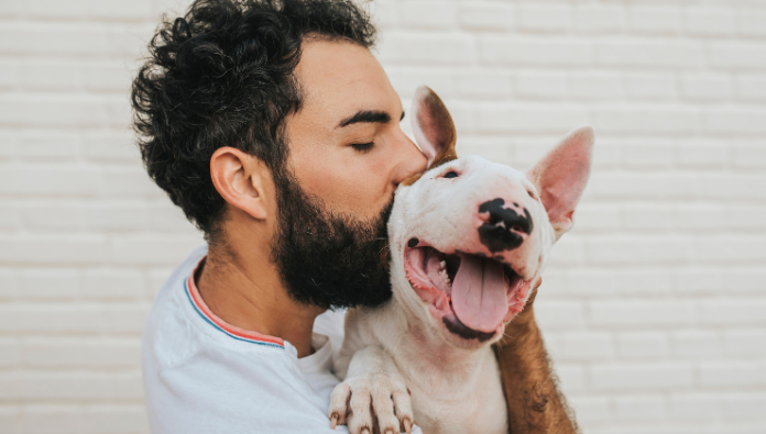 A man kissing his dog on the head A man kissing his dog on the head
